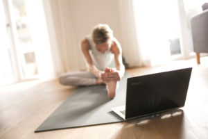 Woman 40+ practices yoga at home with notebook. Online yoga class. Woman 40+ practices yoga at home with notebook. Online yoga class.